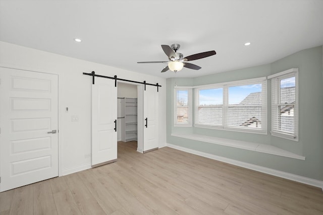 14449 Golf Rd, Orland Park, IL 60462 - unfurnished bedroom with a barn door, light wood-style flooring, multiple windows, recessed lighting, and a spacious closet