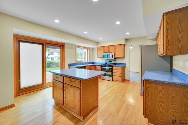 646 Schooner Ln, Elk Grove Village, IL 60007 - kitchen featuring appliances with stainless steel finishes, light wood finished floors, brown cabinets, a kitchen island, and dark countertops