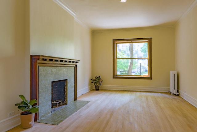 668 W Irving Park Rd Unit H1, Chicago, IL 60613 - unfurnished living room featuring radiator heating unit, wood finished floors, ornamental molding, and a fireplace with flush hearth