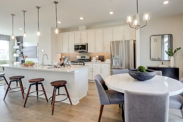 1058 E Oakton St, Des Plaines, IL 60018 - kitchen featuring stainless steel appliances, a breakfast bar, light wood finished floors, tasteful backsplash, and white cabinets
