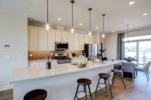 1058 E Oakton St, Des Plaines, IL 60018 - kitchen with stainless steel appliances, wood finished floors, tasteful backsplash, a breakfast bar, and white cabinets