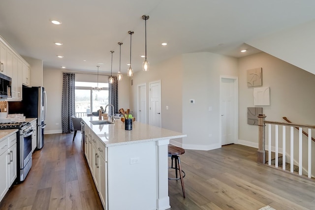 1058 E Oakton St, Des Plaines, IL 60018 - kitchen featuring appliances with stainless steel finishes, a breakfast bar area, white cabinets, a center island with sink, and wood finished floors