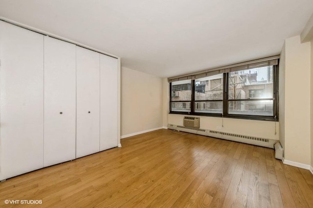 33 E Cedar St Unit 3D, Chicago, IL 60611 - unfurnished bedroom with baseboard heating, light wood finished floors, and a closet