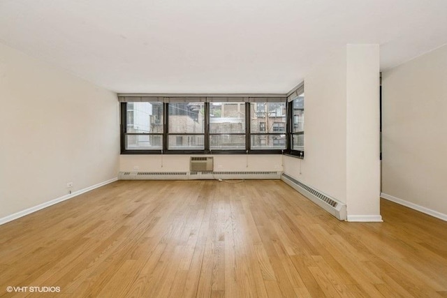 33 E Cedar St Unit 3D, Chicago, IL 60611 - spare room with light wood-style floors, a baseboard heating unit, and a wall mounted air conditioner