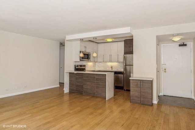 33 E Cedar St Unit 3D, Chicago, IL 60611 - kitchen featuring stainless steel appliances, light countertops, backsplash, a peninsula, and light wood-style flooring