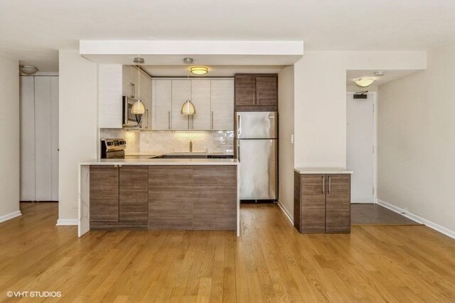 33 E Cedar St Unit 3D, Chicago, IL 60611 - kitchen featuring stainless steel appliances, a peninsula, light countertops, and decorative backsplash