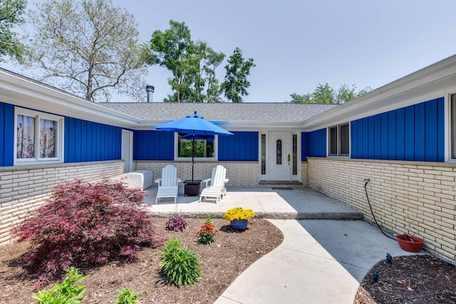 908 Jackson Ave, Wauconda, IL 60084 - doorway to property featuring brick siding, a shingled roof, board and batten siding, and a patio