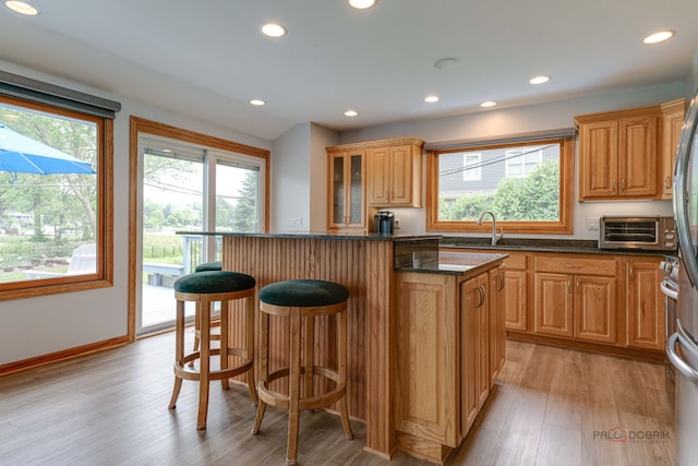 908 Jackson Ave, Wauconda, IL 60084 - kitchen with a kitchen breakfast bar, a center island, light wood-type flooring, recessed lighting, and dark stone countertops