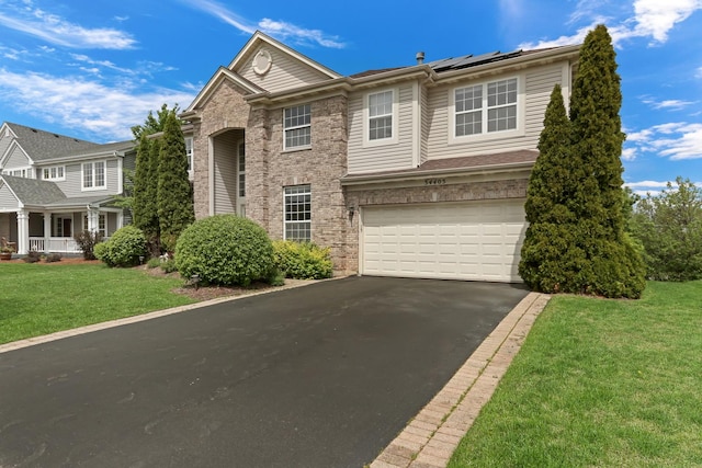 34405 N Bobolink Trl, Grayslake, IL 60030 - view of front facade featuring asphalt driveway, an attached garage, roof mounted solar panels, a front lawn, and brick siding