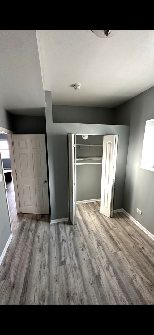 4226 W Ogden, Chicago, IL 60623 - unfurnished bedroom with wood finished floors and a closet