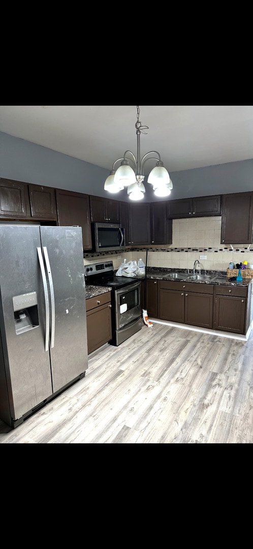 4226 W Ogden, Chicago, IL 60623 - kitchen with appliances with stainless steel finishes, dark countertops, light wood-type flooring, decorative backsplash, and a chandelier