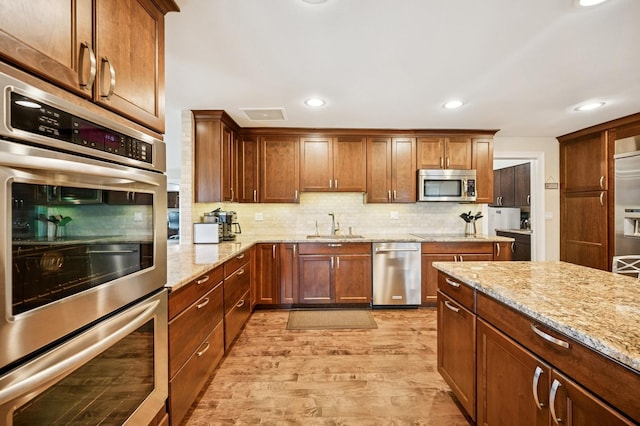 1740 Mission Hills Rd Unit 304, Northbrook, IL 60062 - kitchen with appliances with stainless steel finishes, light wood-style floors, decorative backsplash, light stone counters, and recessed lighting