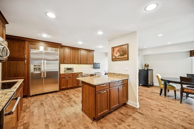 1740 Mission Hills Rd Unit 304, Northbrook, IL 60062 - kitchen featuring stainless steel appliances, a peninsula, light wood-style flooring, light stone countertops, and recessed lighting