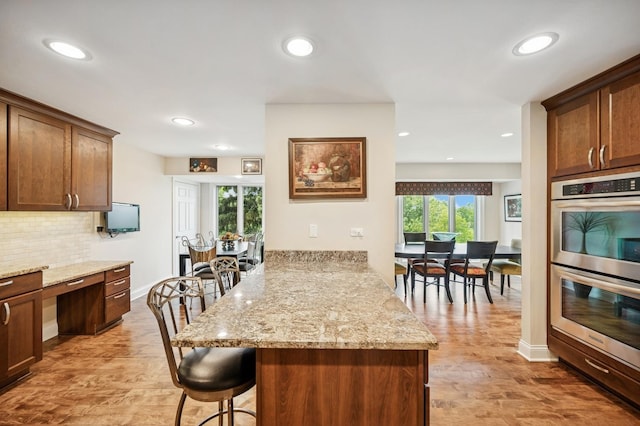 1740 Mission Hills Rd Unit 304, Northbrook, IL 60062 - kitchen with double oven, a peninsula, a kitchen breakfast bar, light stone countertops, and recessed lighting