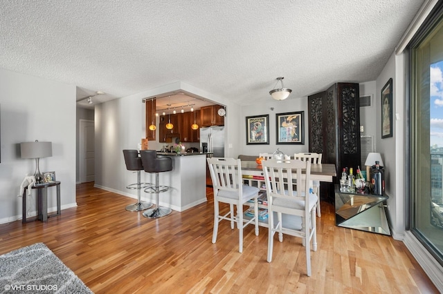70 W Huron St Unit 2202, Chicago, IL 60654 - dining area featuring light wood finished floors, a textured ceiling, bar area, and track lighting