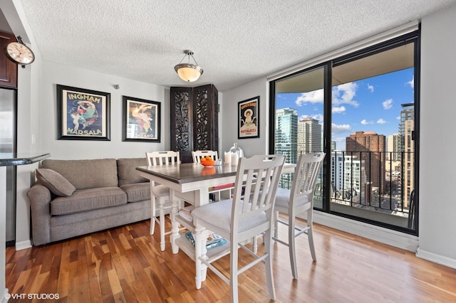 70 W Huron St Unit 2202, Chicago, IL 60654 - dining area featuring wood finished floors, a textured ceiling, a city view, and a wall of windows