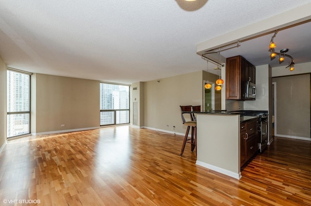 70 W Huron St Unit 2202, Chicago, IL 60654 - kitchen with stainless steel microwave, light wood finished floors, dark countertops, a kitchen bar, and a textured ceiling