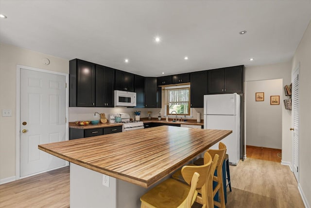 1704 Chevy Chase Dr, Champaign, IL 61821 - kitchen with white appliances, dark cabinetry, butcher block countertops, a kitchen bar, and light wood-style floors