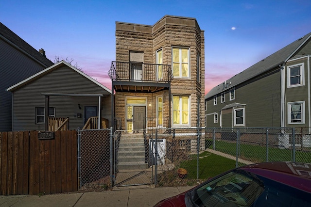 5522 S Wells St, Chicago, IL 60621 - front facade featuring a balcony, a gate, a fenced front yard, and stone siding