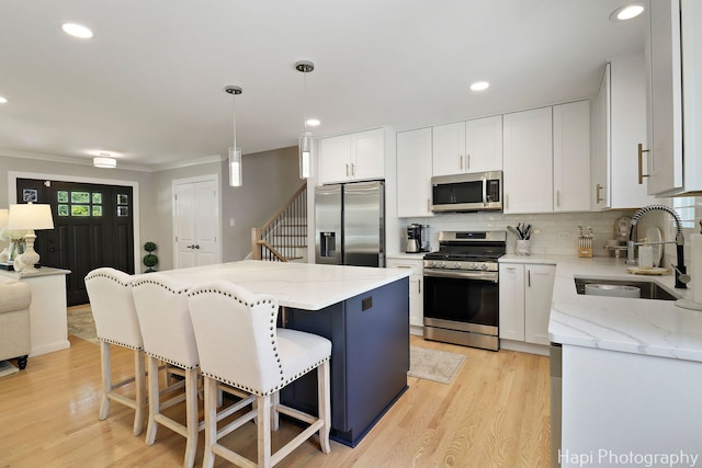 813 E Gardenia Ln, Palatine, IL 60074 - kitchen featuring appliances with stainless steel finishes, a kitchen breakfast bar, light wood-style flooring, decorative backsplash, and ornamental molding