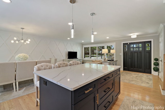 813 E Gardenia Ln, Palatine, IL 60074 - kitchen featuring light wood-style floors, ornamental molding, open floor plan, a center island, and light stone countertops