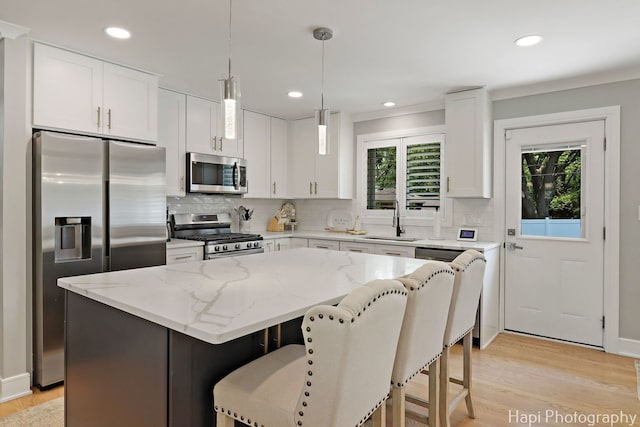 813 E Gardenia Ln, Palatine, IL 60074 - kitchen with appliances with stainless steel finishes, a kitchen island, tasteful backsplash, light wood finished floors, and light stone counters