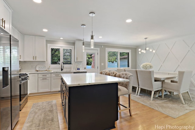 813 E Gardenia Ln, Palatine, IL 60074 - kitchen featuring stainless steel appliances, white cabinetry, ornamental molding, a breakfast bar, and backsplash