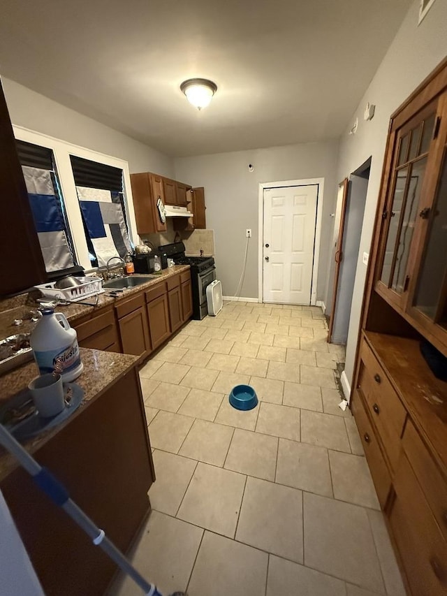 7544 S Sangamon St, Chicago, IL 60620 - kitchen with stainless steel gas range, under cabinet range hood, dark countertops, light tile patterned flooring, and brown cabinetry