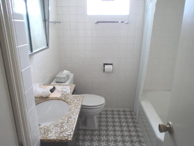 7341 W 56th Pl, Summit, IL 60501 - bathroom with tile patterned floors, vanity, tile walls, and shower / tub combo with curtain