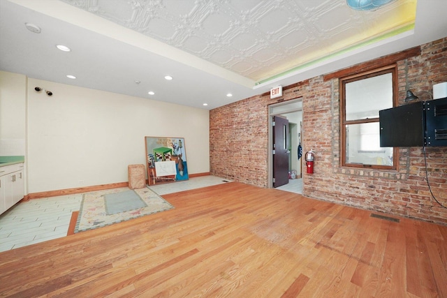 2347 Clarence Ave, Berwyn, IL 60402 - unfurnished living room with wood finished floors, brick wall, a tray ceiling, an ornate ceiling, and recessed lighting