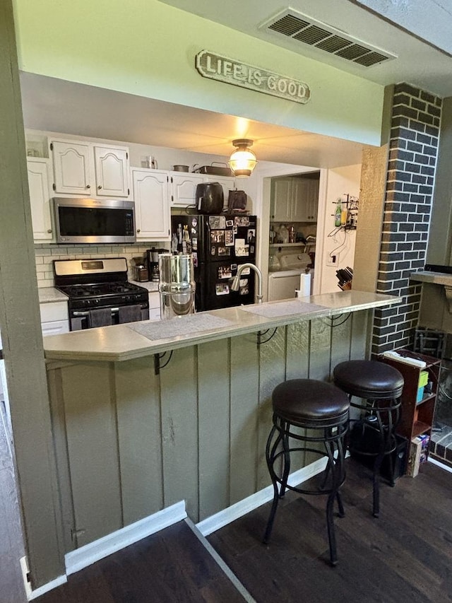847 Teverton Ln, Crystal Lake, IL 60014 - kitchen featuring appliances with stainless steel finishes, dark wood-style floors, white cabinets, a breakfast bar, and light countertops