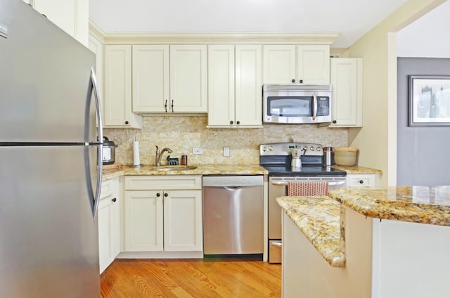 405 N Wabash Ave Unit 2211, Chicago, IL 60611 - kitchen featuring appliances with stainless steel finishes, light wood-style flooring, backsplash, light stone countertops, and cream cabinets