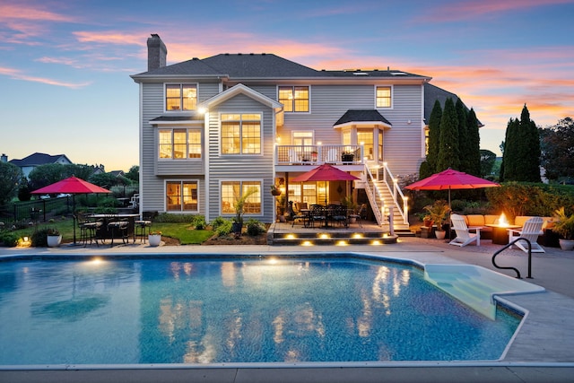 38W385 Stevens Glen Rd, Saint Charles, IL 60175 - back of house at dusk with outdoor dining area, a chimney, stairway, and an outdoor pool