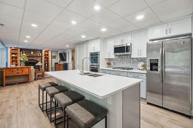 38W385 Stevens Glen Rd, Saint Charles, IL 60175 - kitchen with stainless steel appliances, a breakfast bar area, light wood finished floors, a kitchen island with sink, and white cabinets