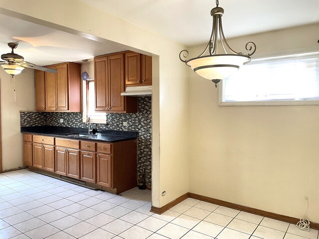 3909 W 71st St, Chicago, IL 60629 - kitchen with under cabinet range hood, dark countertops, ceiling fan, decorative backsplash, and brown cabinetry