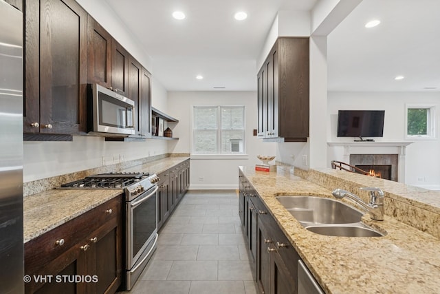 2835 N Lakewood Ave Unit 2C, Chicago, IL 60657 - kitchen featuring stainless steel appliances, dark brown cabinets, a fireplace, light stone countertops, and recessed lighting