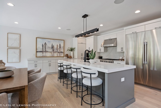 20 Pinnacle Ct, Naperville, IL 60565 - kitchen featuring built in fridge, range hood, a kitchen bar, light wood finished floors, and recessed lighting