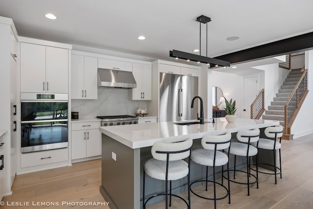 20 Pinnacle Ct, Naperville, IL 60565 - kitchen with ventilation hood, stainless steel appliances, light wood-style floors, an island with sink, and a breakfast bar area