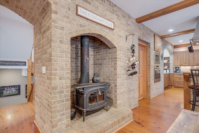 2 Timber Ridge Ln, Mansfield, IL 61854 - detailed view of stainless steel appliances, wood finished floors, a wood stove, beamed ceiling, and brick wall