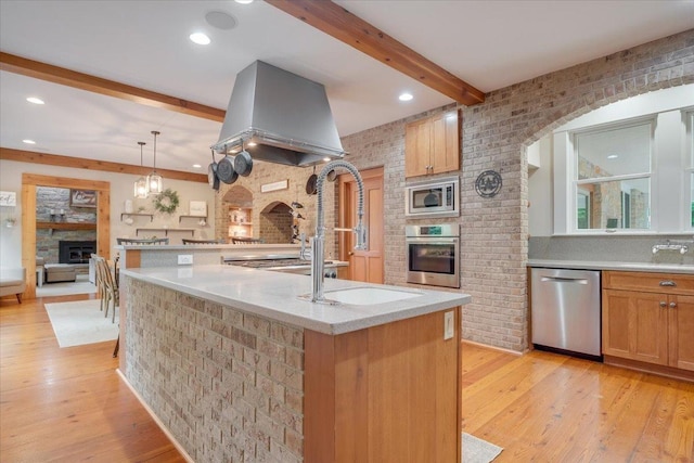 2 Timber Ridge Ln, Mansfield, IL 61854 - kitchen featuring appliances with stainless steel finishes, a fireplace, beam ceiling, island range hood, and light wood-style floors