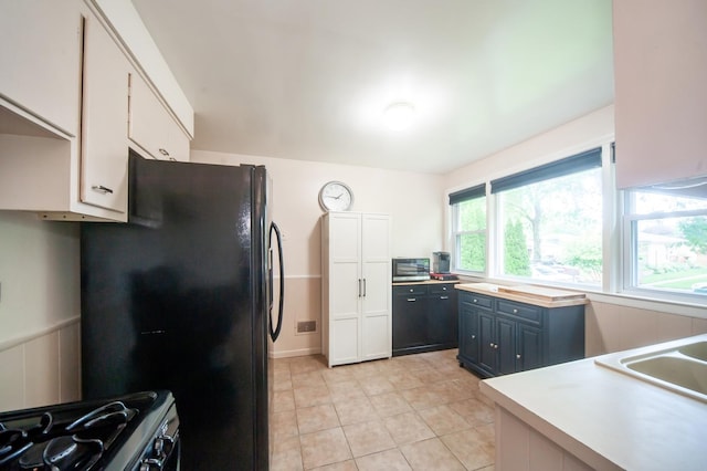 928 Grey Ave, Evanston, IL 60202 - kitchen with range with gas stovetop, freestanding refrigerator, white cabinets, light countertops, and light tile patterned floors
