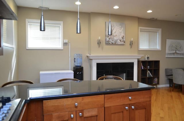 4435 S Oakenwald Ave Unit 1, Chicago, IL 60653 - kitchen featuring dark countertops, light wood-style flooring, brown cabinets, a fireplace, and recessed lighting