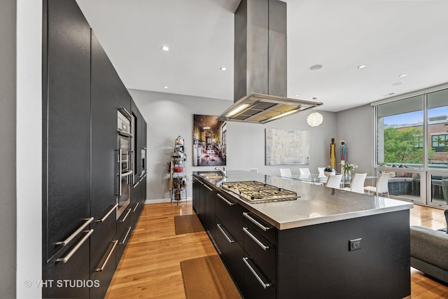 1711 W Division St Unit 303, Chicago, IL 60622 - kitchen with dark cabinets, island range hood, modern cabinets, light wood finished floors, and stainless steel gas stovetop