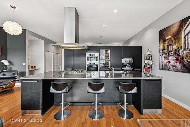 1711 W Division St Unit 303, Chicago, IL 60622 - kitchen with island range hood, modern cabinets, light wood-style floors, dark cabinets, and a kitchen bar