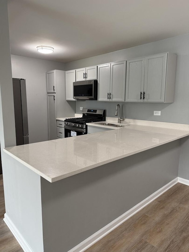 907 Gael Dr Unit D, Joliet, IL 60435 - kitchen featuring appliances with stainless steel finishes, dark wood-type flooring, a peninsula, a breakfast bar area, and light stone counters