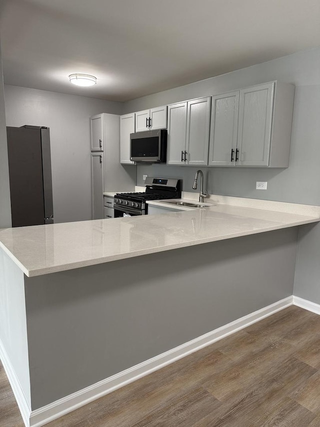 907 Gael Dr Unit D, Joliet, IL 60435 - kitchen featuring stainless steel appliances, dark wood finished floors, a peninsula, and a kitchen breakfast bar