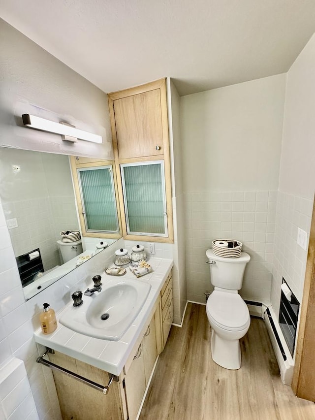 221 Thornbrook Rd, Dekalb, IL 60115 - half bath with tile walls, wood finished floors, vanity, a baseboard radiator, and a wainscoted wall