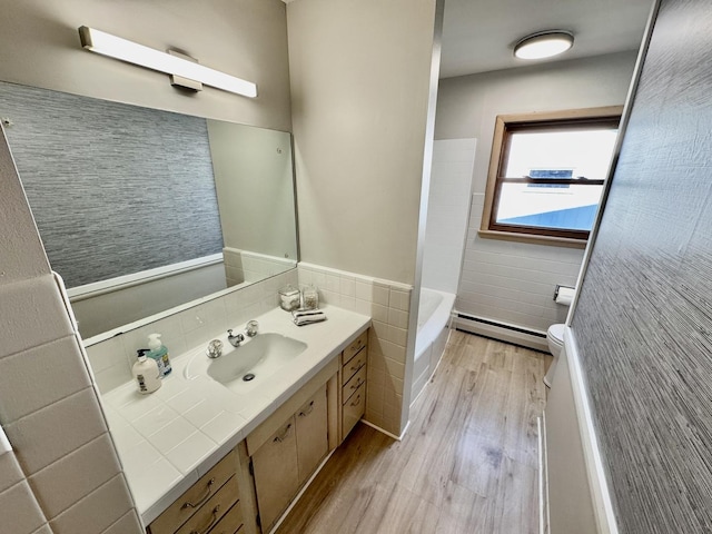 221 Thornbrook Rd, Dekalb, IL 60115 - bathroom featuring baseboard heating, tile walls, vanity, wood finished floors, and a tub