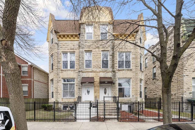 3612 S Prairie Ave Unit 2, Chicago, IL 60653 - view of property featuring stone siding, a gate, a fenced front yard, and a chimney