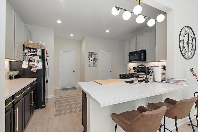 1526 Peachtree Ln, Lockport, IL 60441 - kitchen featuring black appliances, light wood-style flooring, a peninsula, a kitchen bar, and recessed lighting